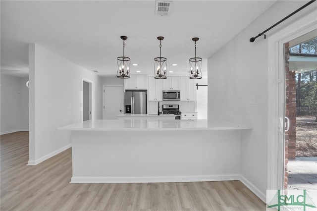 kitchen featuring decorative light fixtures, white cabinetry, light hardwood / wood-style floors, kitchen peninsula, and stainless steel appliances