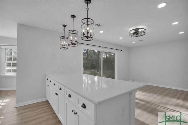 kitchen with pendant lighting, plenty of natural light, white cabinets, and light hardwood / wood-style flooring