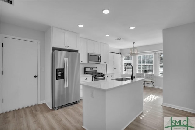 kitchen featuring decorative light fixtures, white cabinetry, sink, a kitchen island with sink, and stainless steel appliances