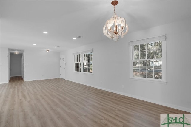 unfurnished room featuring an inviting chandelier and light hardwood / wood-style flooring