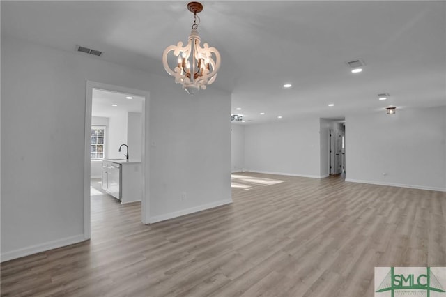 interior space featuring sink, a notable chandelier, and light wood-type flooring