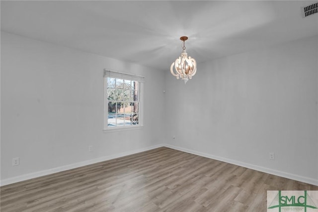 unfurnished room featuring light hardwood / wood-style flooring and a chandelier