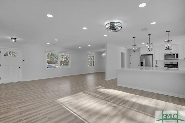 101 Cromwell Ct, Savannah, GA 31410 - unfurnished living room featuring an inviting chandelier, baseboards, light wood-type flooring, and recessed lighting