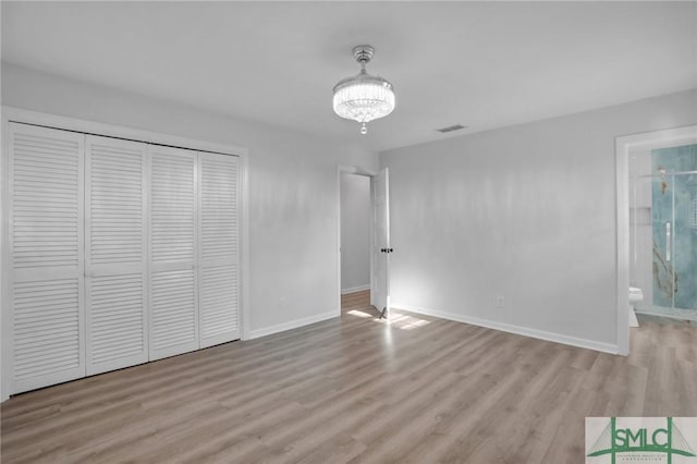 interior space featuring light hardwood / wood-style flooring, a closet, a chandelier, and ensuite bathroom