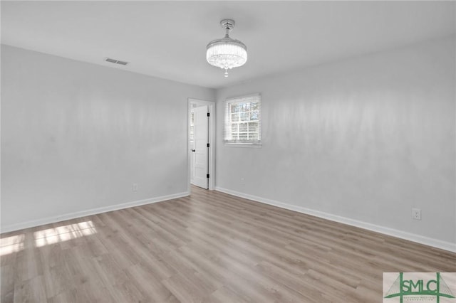 unfurnished room with light hardwood / wood-style flooring and a notable chandelier