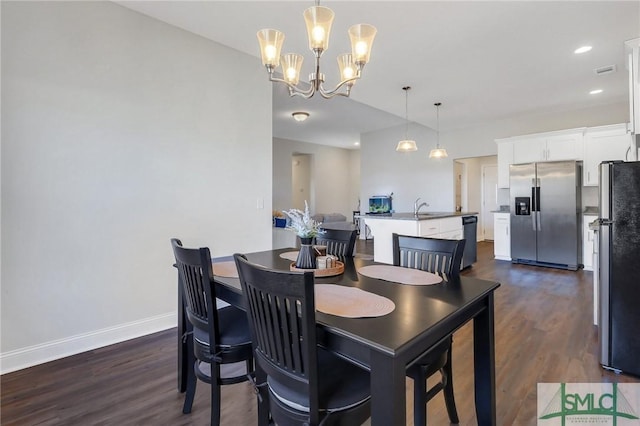 dining space featuring dark hardwood / wood-style flooring, a chandelier, and sink