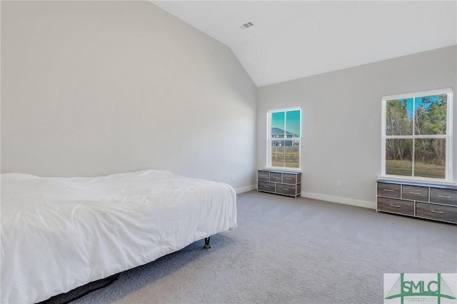 bedroom with multiple windows, lofted ceiling, and light colored carpet