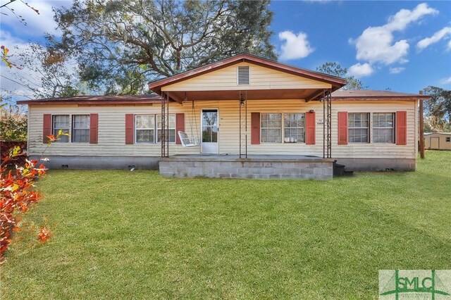 rear view of property featuring a lawn and covered porch