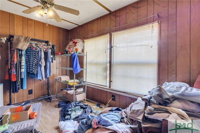 miscellaneous room with ceiling fan, light wood-type flooring, and wood walls