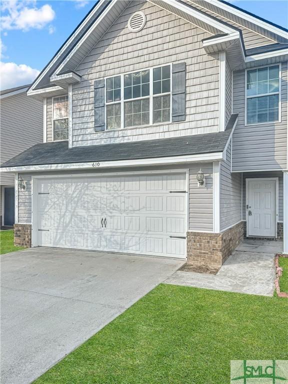 view of property featuring a garage and a front lawn