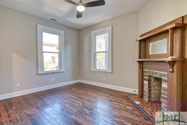 unfurnished living room with dark wood-type flooring, ceiling fan, a healthy amount of sunlight, and a fireplace