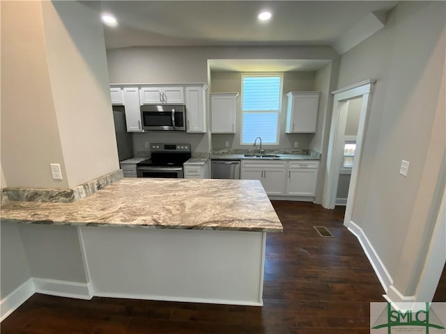 kitchen featuring sink, light stone counters, appliances with stainless steel finishes, kitchen peninsula, and white cabinets