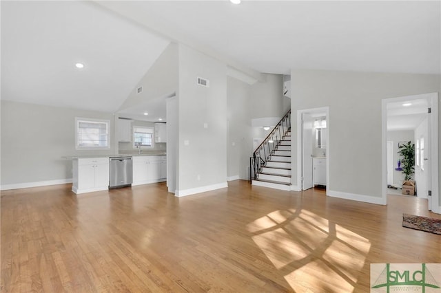 unfurnished living room with high vaulted ceiling and light hardwood / wood-style flooring