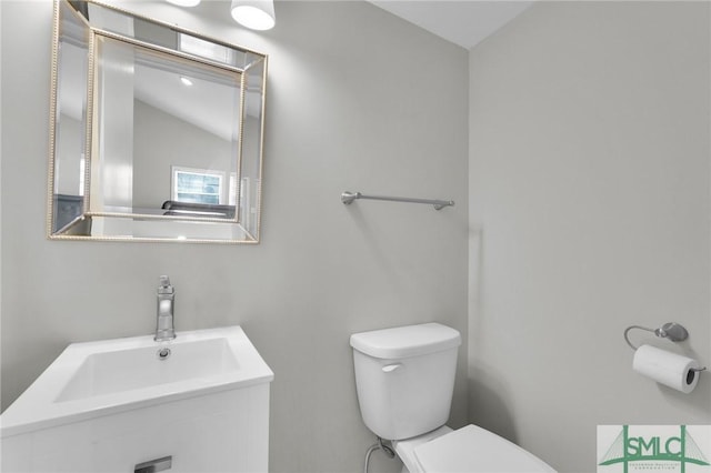 bathroom with sink, toilet, and vaulted ceiling