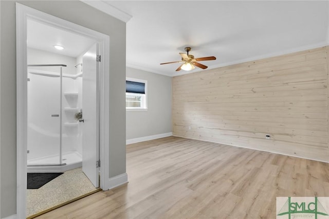 interior space with light hardwood / wood-style flooring, ornamental molding, ceiling fan, and wood walls