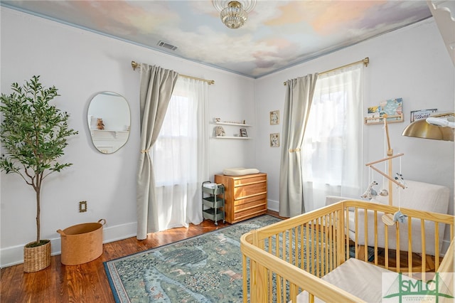 bedroom featuring multiple windows, hardwood / wood-style flooring, and a nursery area