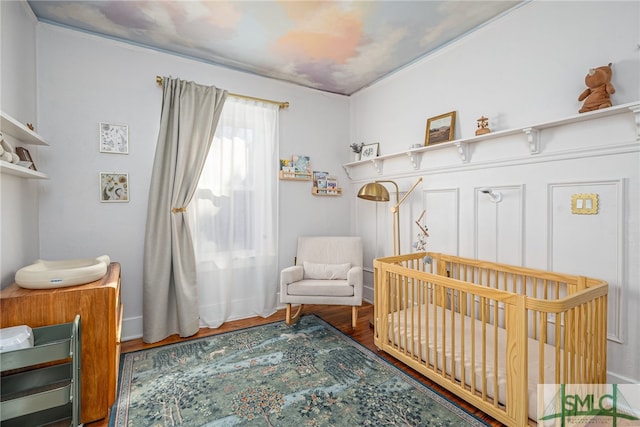 bedroom with hardwood / wood-style flooring and a crib