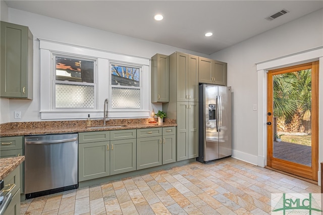 kitchen featuring sink, dark stone countertops, green cabinets, stainless steel appliances, and a healthy amount of sunlight