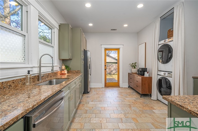 kitchen with green cabinets, stainless steel appliances, stacked washer / dryer, and sink