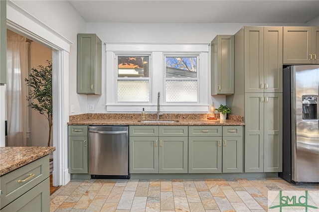 kitchen featuring light stone counters, sink, stainless steel appliances, and green cabinetry