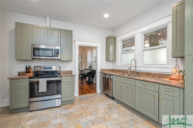 kitchen featuring dark stone countertops, sink, stainless steel appliances, and green cabinetry