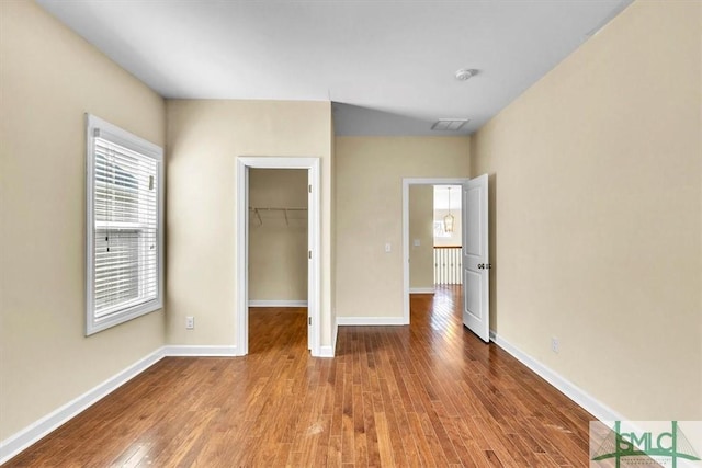 unfurnished bedroom with hardwood / wood-style flooring, a spacious closet, and a closet