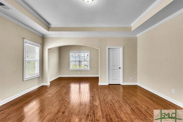 empty room with plenty of natural light, ornamental molding, and wood-type flooring