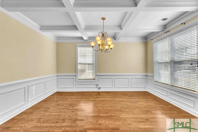 spare room featuring beamed ceiling, a chandelier, and light hardwood / wood-style flooring