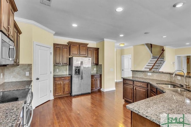 kitchen with sink, crown molding, appliances with stainless steel finishes, light stone counters, and dark hardwood / wood-style flooring