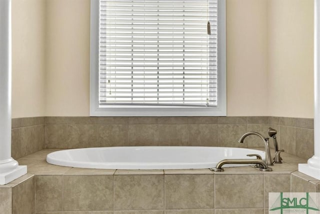 bathroom with tiled bath and decorative columns