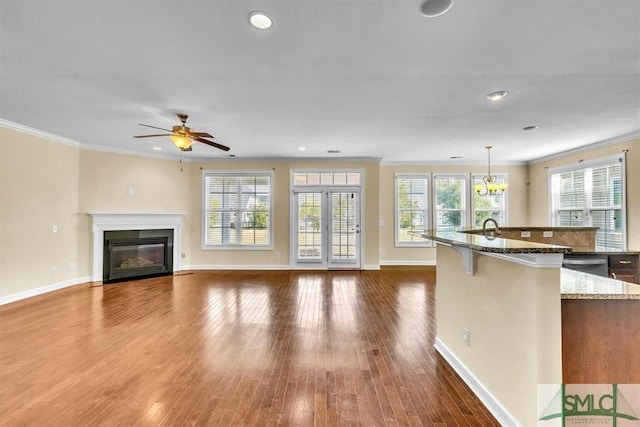 kitchen with hanging light fixtures, crown molding, dark wood-type flooring, and a breakfast bar