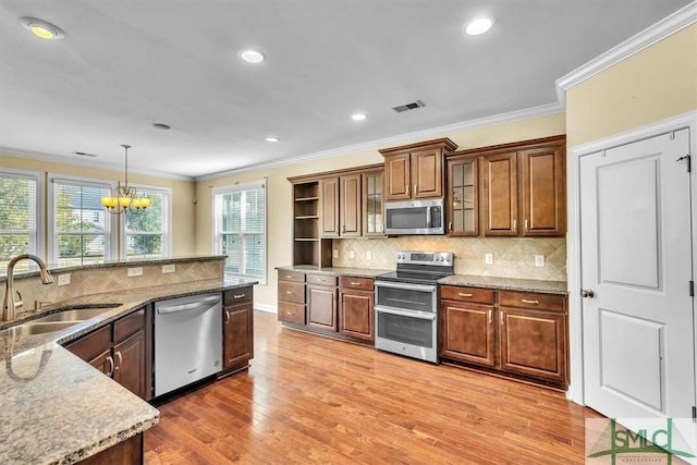 kitchen featuring ornamental molding, appliances with stainless steel finishes, decorative light fixtures, and sink