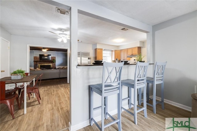 kitchen with a fireplace, a kitchen breakfast bar, kitchen peninsula, and light wood-type flooring