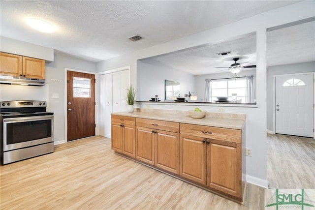 kitchen with stainless steel electric range oven, ceiling fan, a textured ceiling, and light wood-type flooring