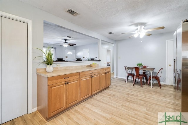 kitchen with ceiling fan, a textured ceiling, and light hardwood / wood-style floors