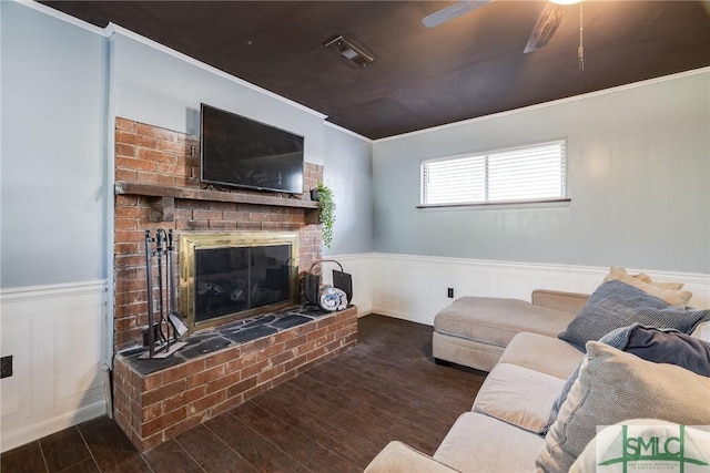 living room with a brick fireplace, crown molding, dark hardwood / wood-style floors, and ceiling fan