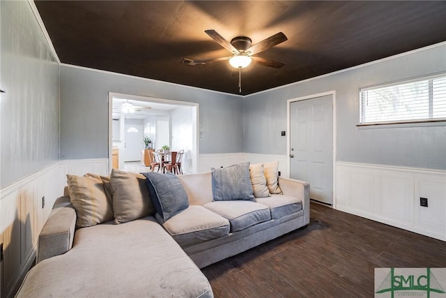 living room with dark hardwood / wood-style flooring, crown molding, and ceiling fan