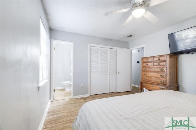 bedroom featuring ceiling fan, ensuite bath, light hardwood / wood-style floors, and a closet