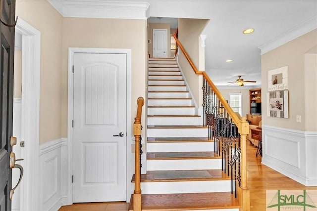 stairway featuring crown molding, ceiling fan, and hardwood / wood-style flooring