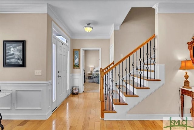 foyer with ornamental molding and light hardwood / wood-style floors