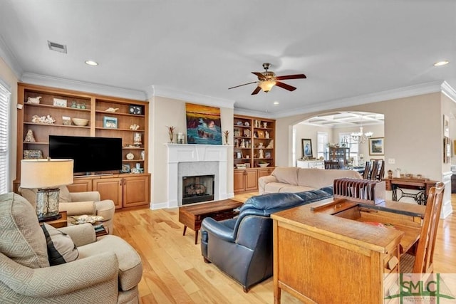 living room with crown molding, ceiling fan with notable chandelier, and light wood-type flooring