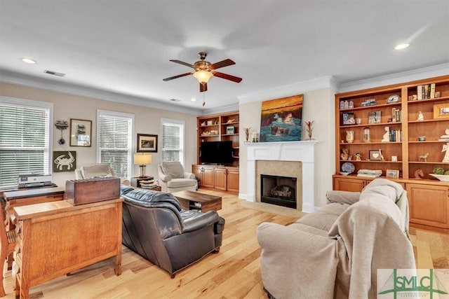 living room with a wealth of natural light, light hardwood / wood-style floors, a premium fireplace, and ceiling fan