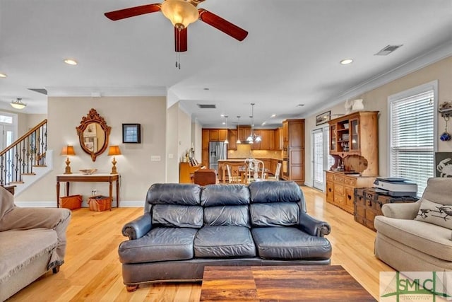 living room featuring crown molding, ceiling fan, and light wood-type flooring