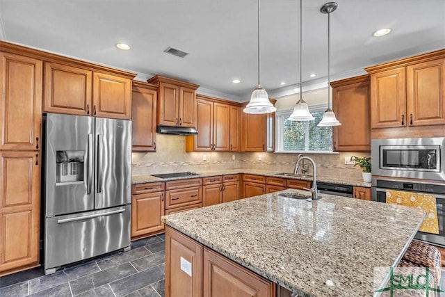 kitchen with a kitchen island with sink, stainless steel appliances, tasteful backsplash, light stone countertops, and decorative light fixtures