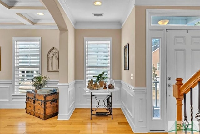 entryway with plenty of natural light, ornamental molding, and light wood-type flooring