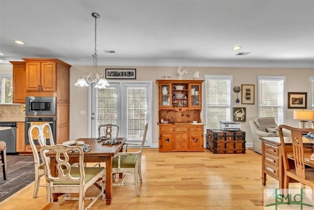 dining room featuring ornamental molding, plenty of natural light, a notable chandelier, and light hardwood / wood-style flooring