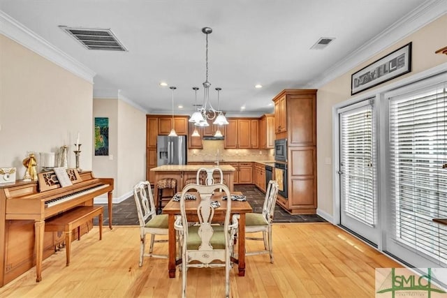 dining room with ornamental molding, sink, and light wood-type flooring