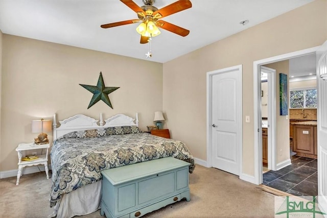 bedroom with ceiling fan, ensuite bath, and dark colored carpet