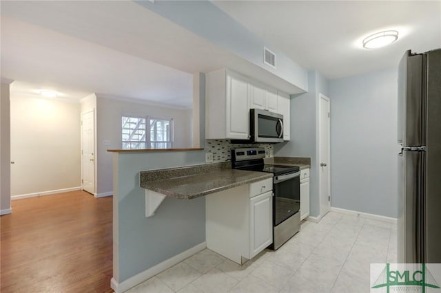 kitchen featuring white cabinetry, crown molding, appliances with stainless steel finishes, kitchen peninsula, and decorative backsplash