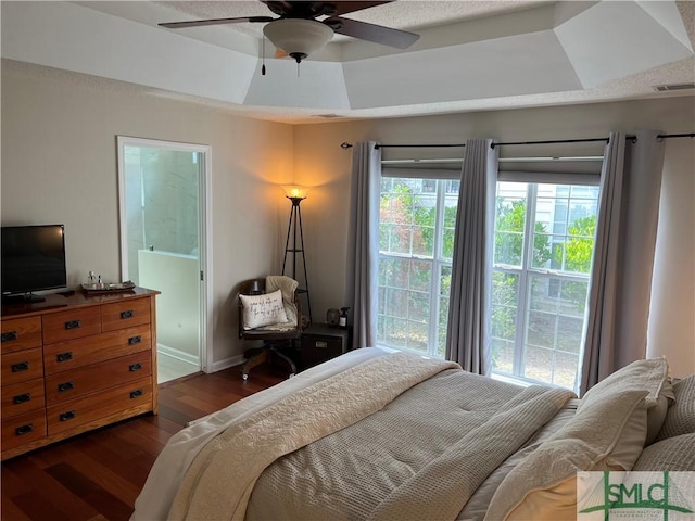 bedroom with ceiling fan, dark hardwood / wood-style flooring, and a tray ceiling